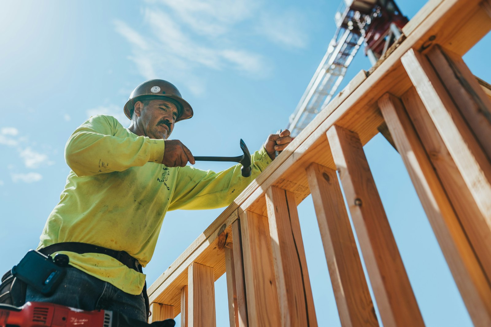 Builder fixing a timber wall frame on a house construction site